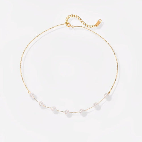Gold necklace with small pearls on a light gray background