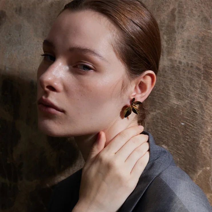 Woman adjusting an earring against a textured wall