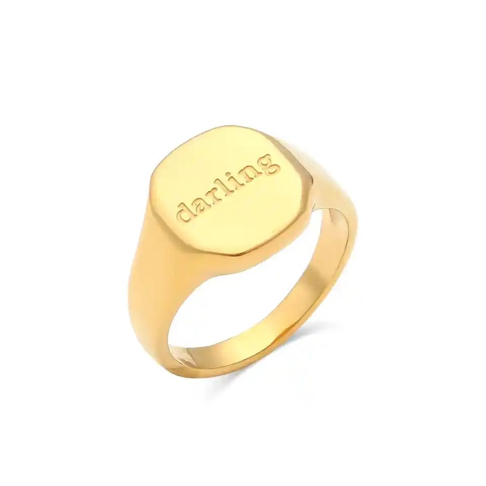 Gold ring with 'darling' engraving on a white background