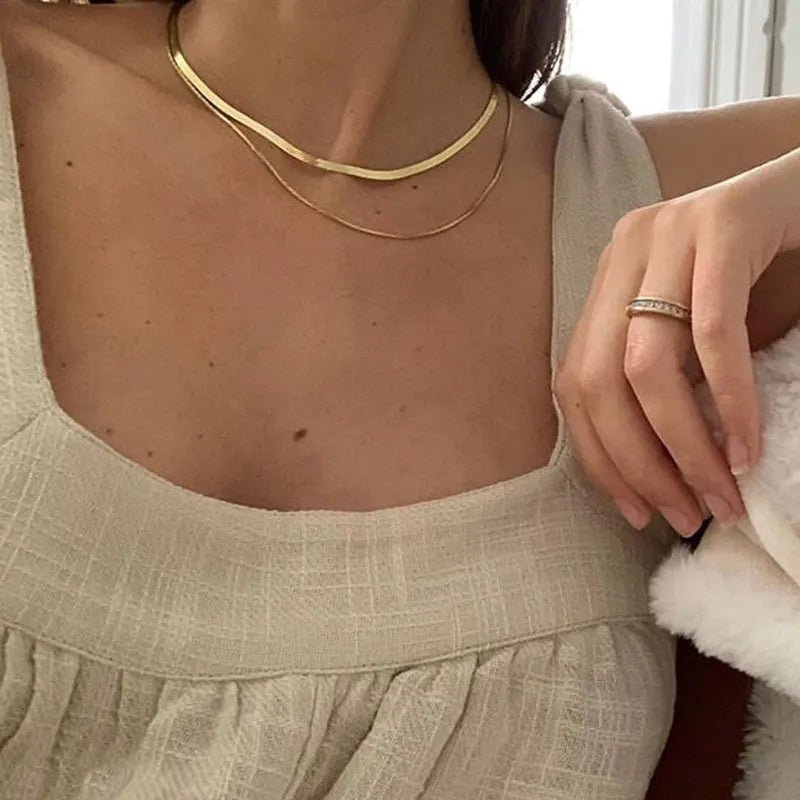 Close-up of a person wearing a gold necklace and beige top.