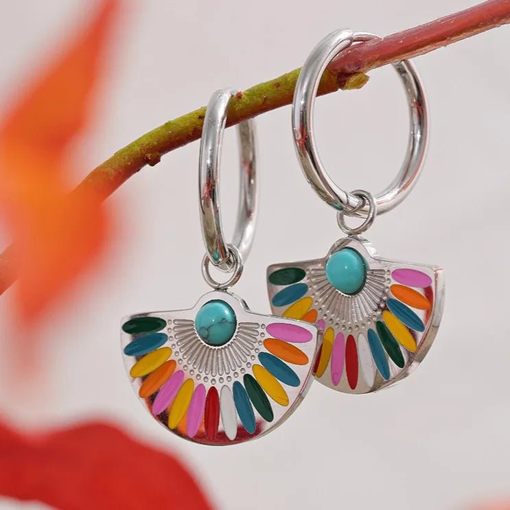 Colorful earrings with a silver half-circle design hanging on a branch.