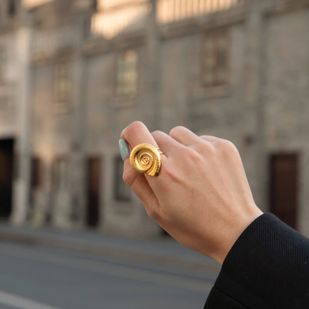 Hand holding a gold ring with a blurred street background