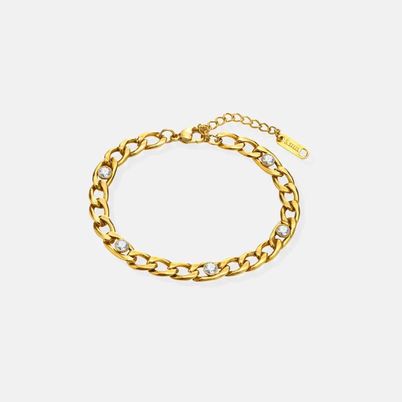Gold chain bracelet with embedded stones on a light gray background