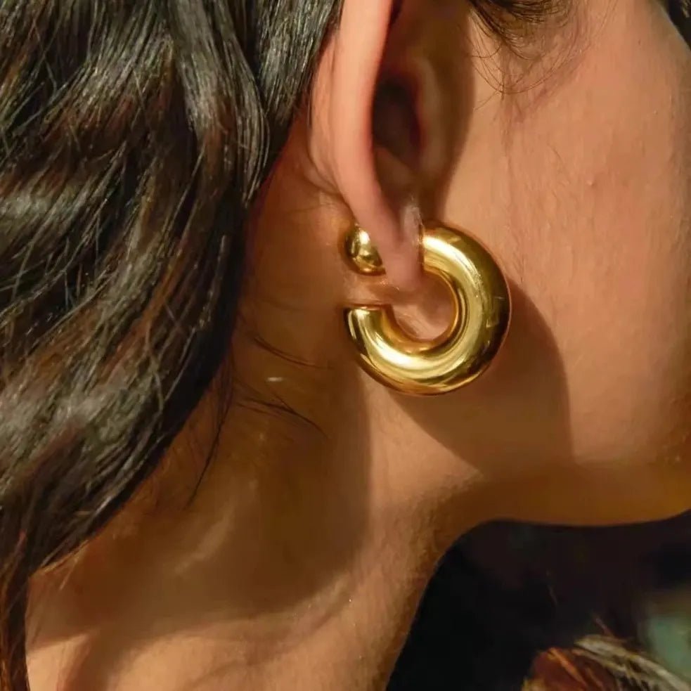 Close-up of a person wearing a gold hoop earring.