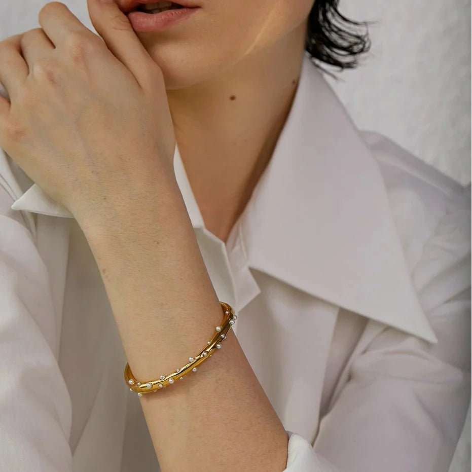 Gold bracelet on a person wearing a white shirt