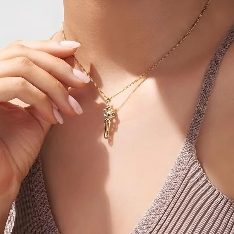 Gold necklace with a pendant worn by a person, focusing on the jewelry.
