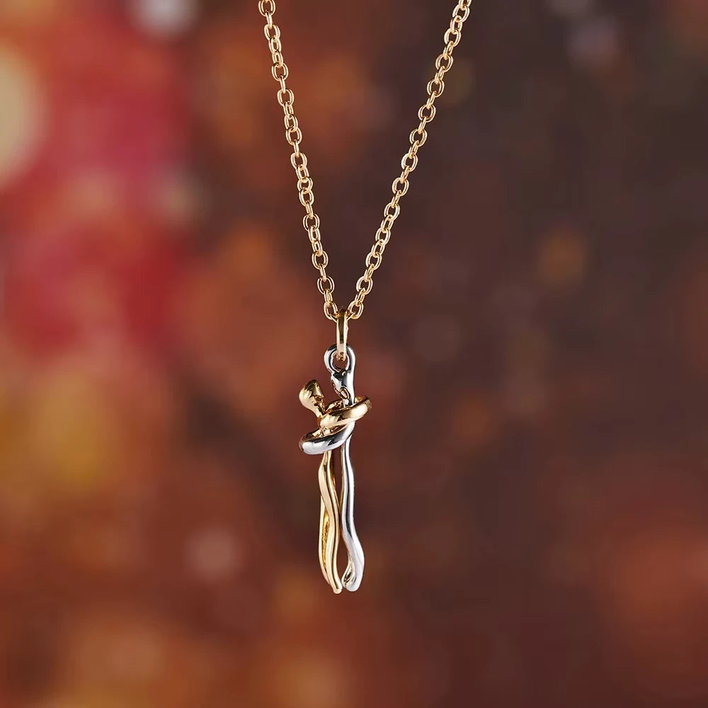 Gold and silver cat-shaped pendant on a chain against a blurred autumn leaf background