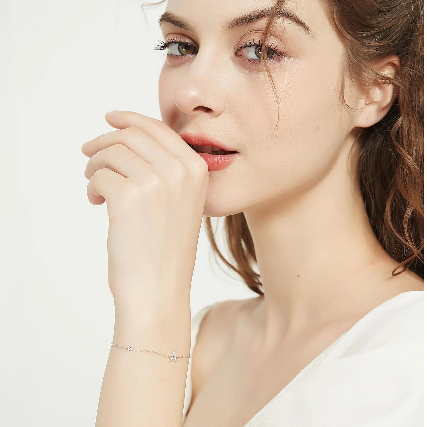 Close-up of a woman wearing a delicate bracelet on a plain background