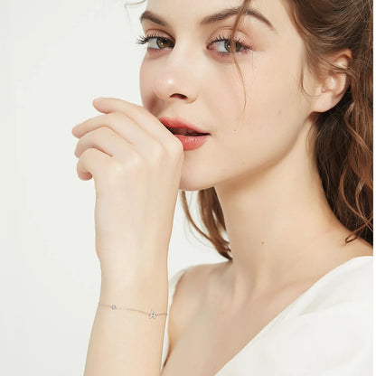 Close-up of a woman wearing a delicate bracelet on a plain background