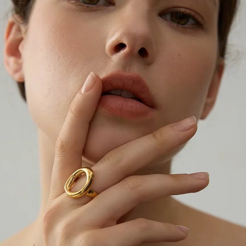 Close-up of a person wearing a gold ring on a neutral background