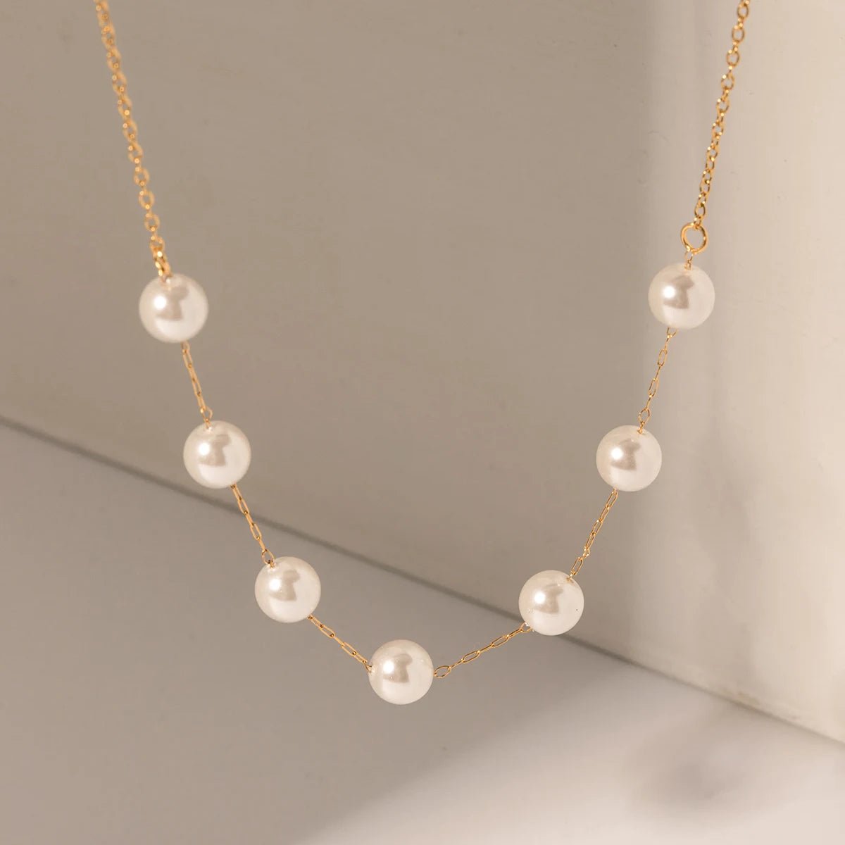 Pearl necklace with gold chain on a neutral background