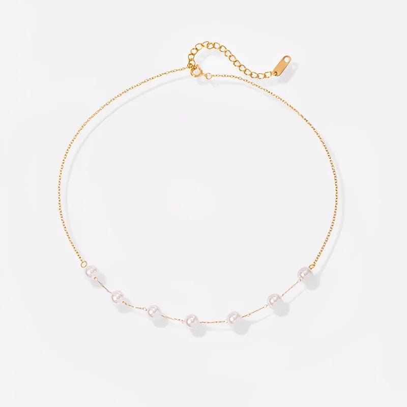 Gold necklace with small pearls on a light gray background