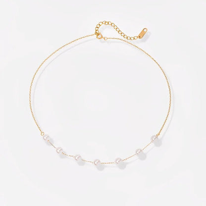 Gold necklace with small pearls on a light gray background