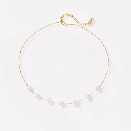 Gold necklace with small pearls on a light gray background