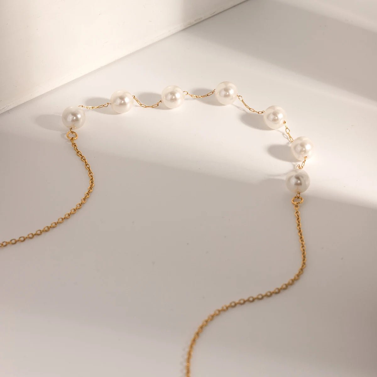 Gold chain necklace with pearls on a white surface