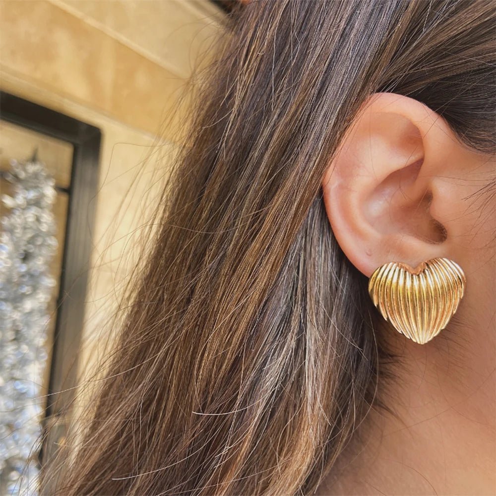 Close-up of an ear wearing a gold earring with blurred background