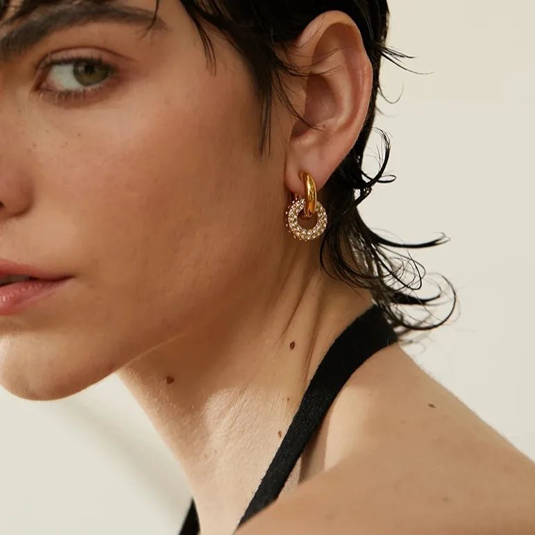 Close-up of a woman wearing gold hoop earrings with a blurred background