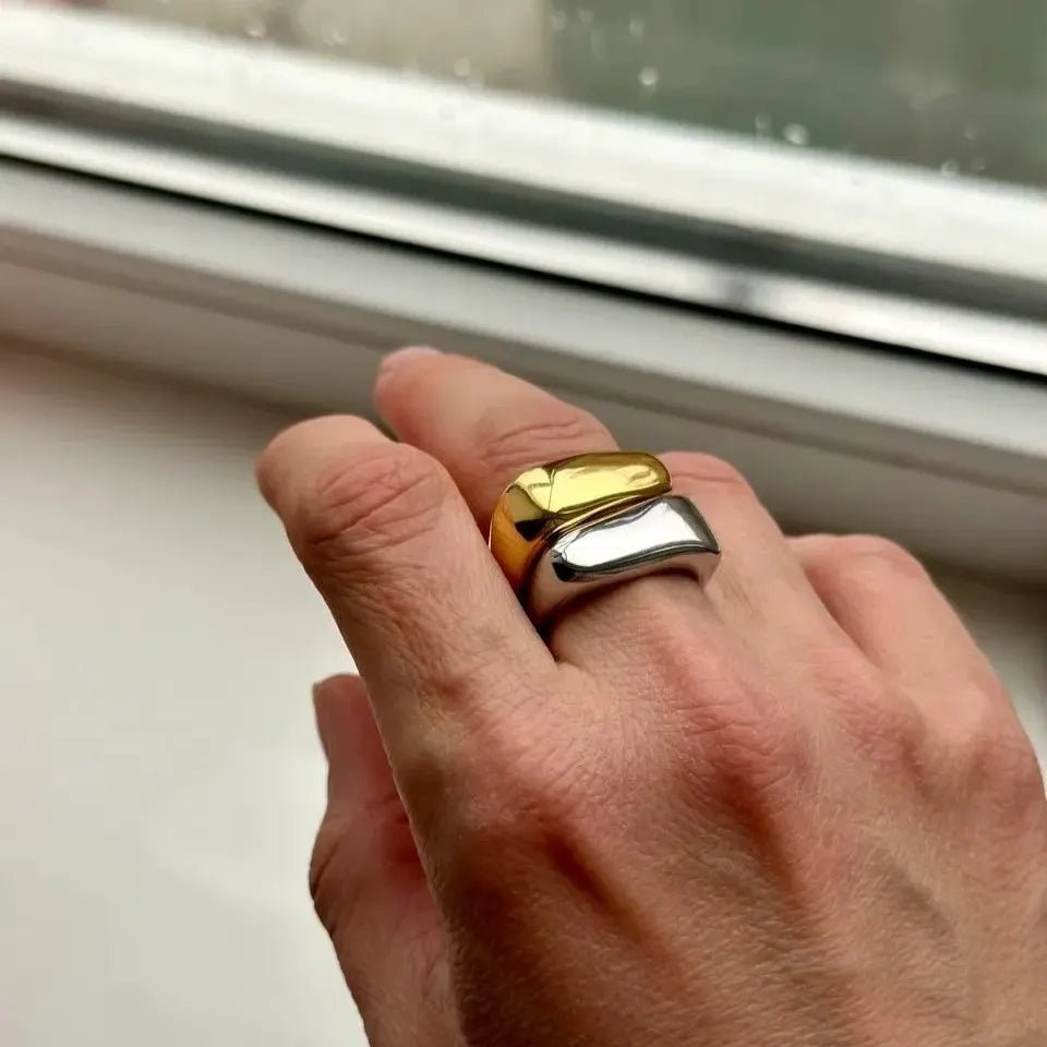 Hand wearing a gold and silver ring with a blurred background