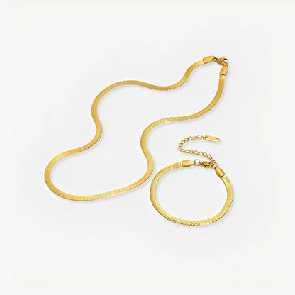 Gold necklace and bracelet set on a light gray background