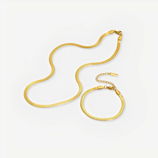 Gold necklace and bracelet set on a light gray background