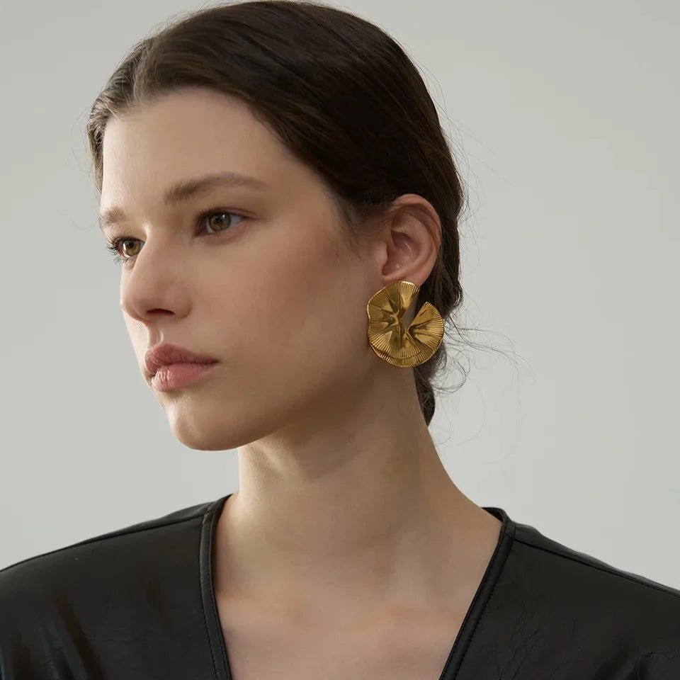 Woman wearing gold earrings against a neutral background