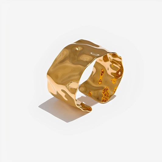 Gold cuff bracelet on a light gray background