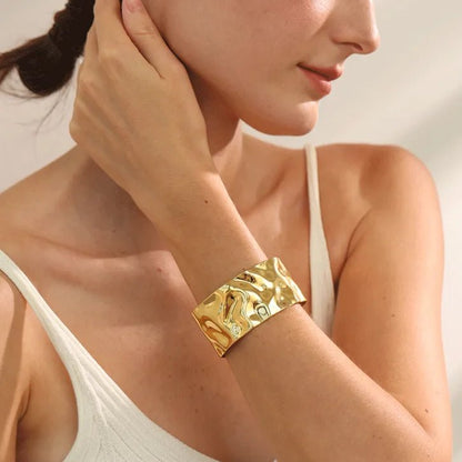 Woman wearing a gold bracelet on her wrist with a neutral background