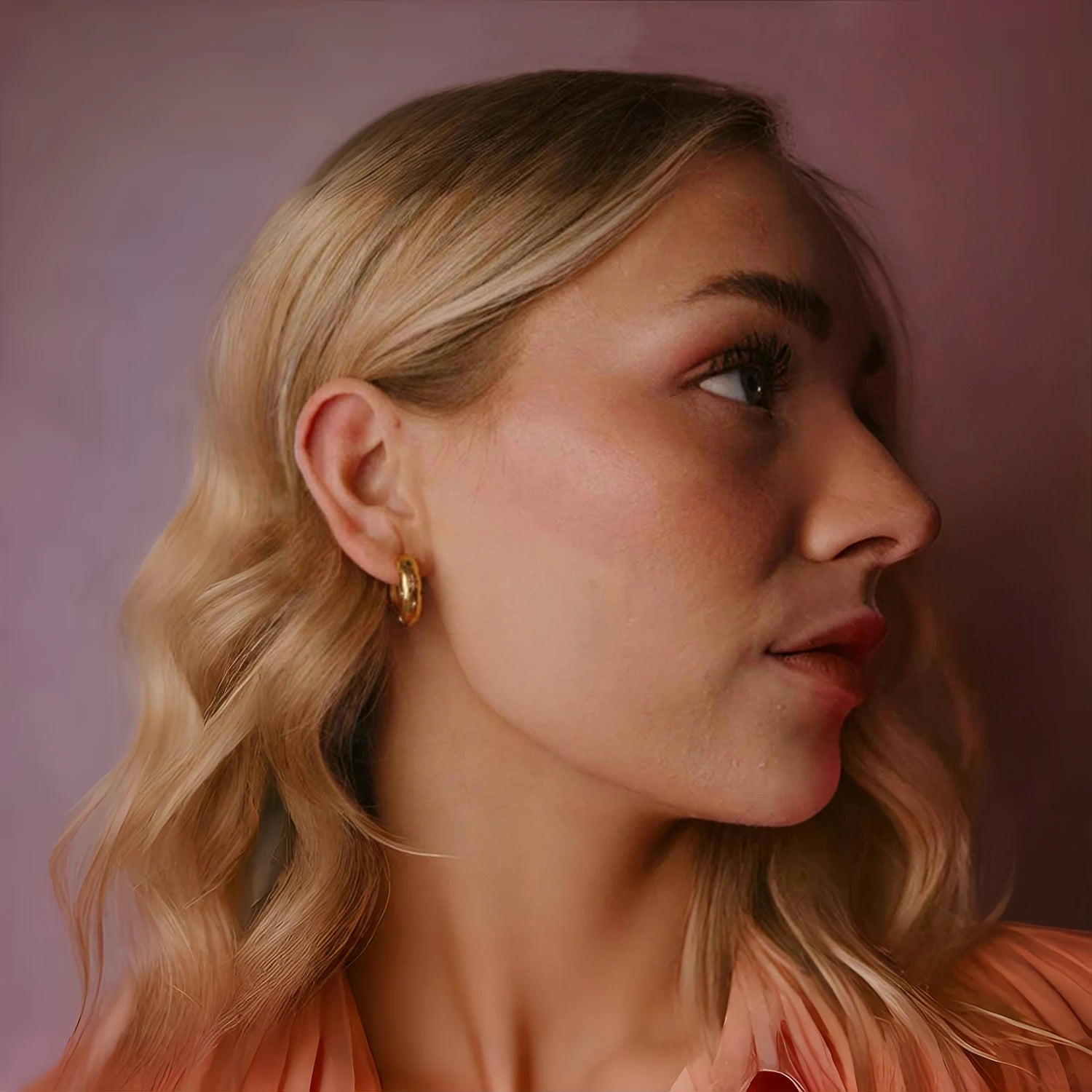 Close-up of a woman with blonde hair and a pink background