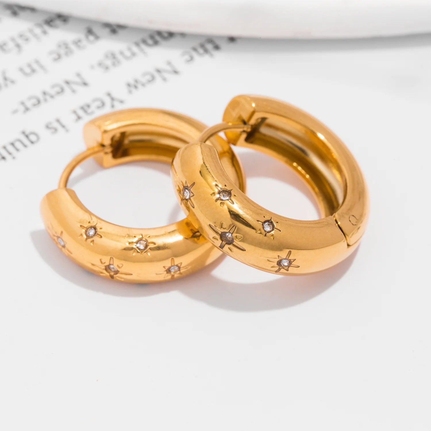 Gold hoop earrings with embedded stones on a white surface