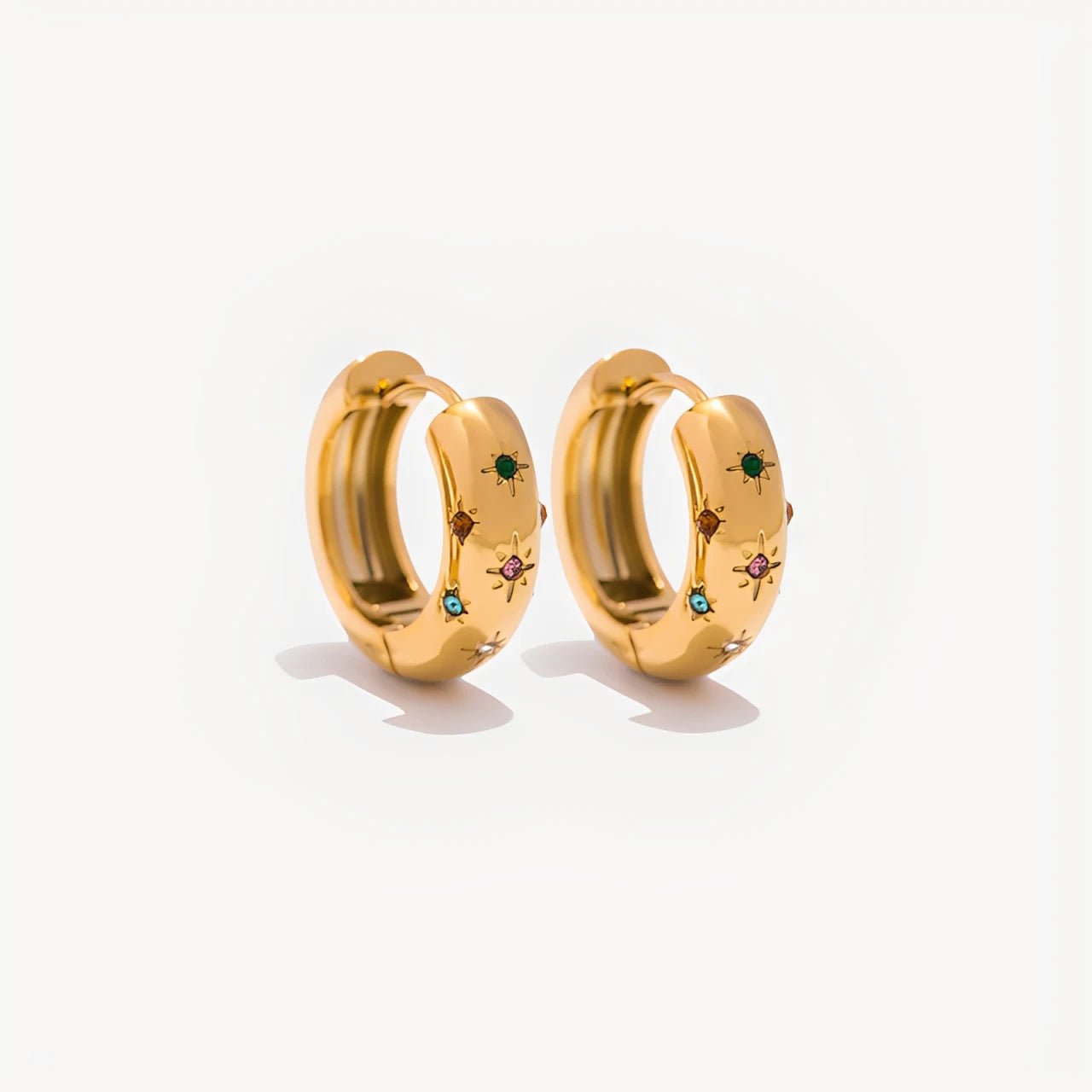 Gold hoop earrings with embedded gemstones on a white background
