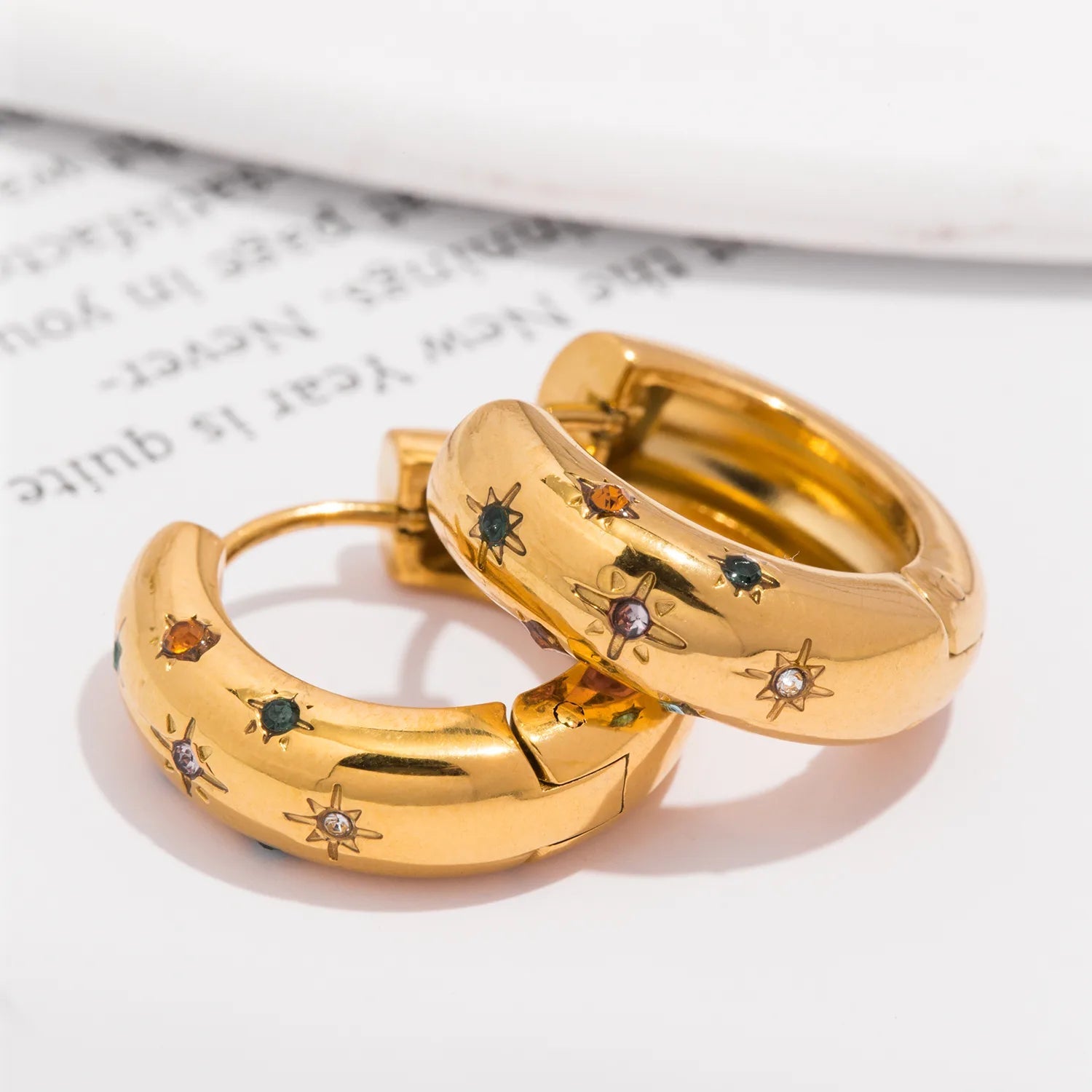 Gold hoop earrings with gemstone accents on a light background