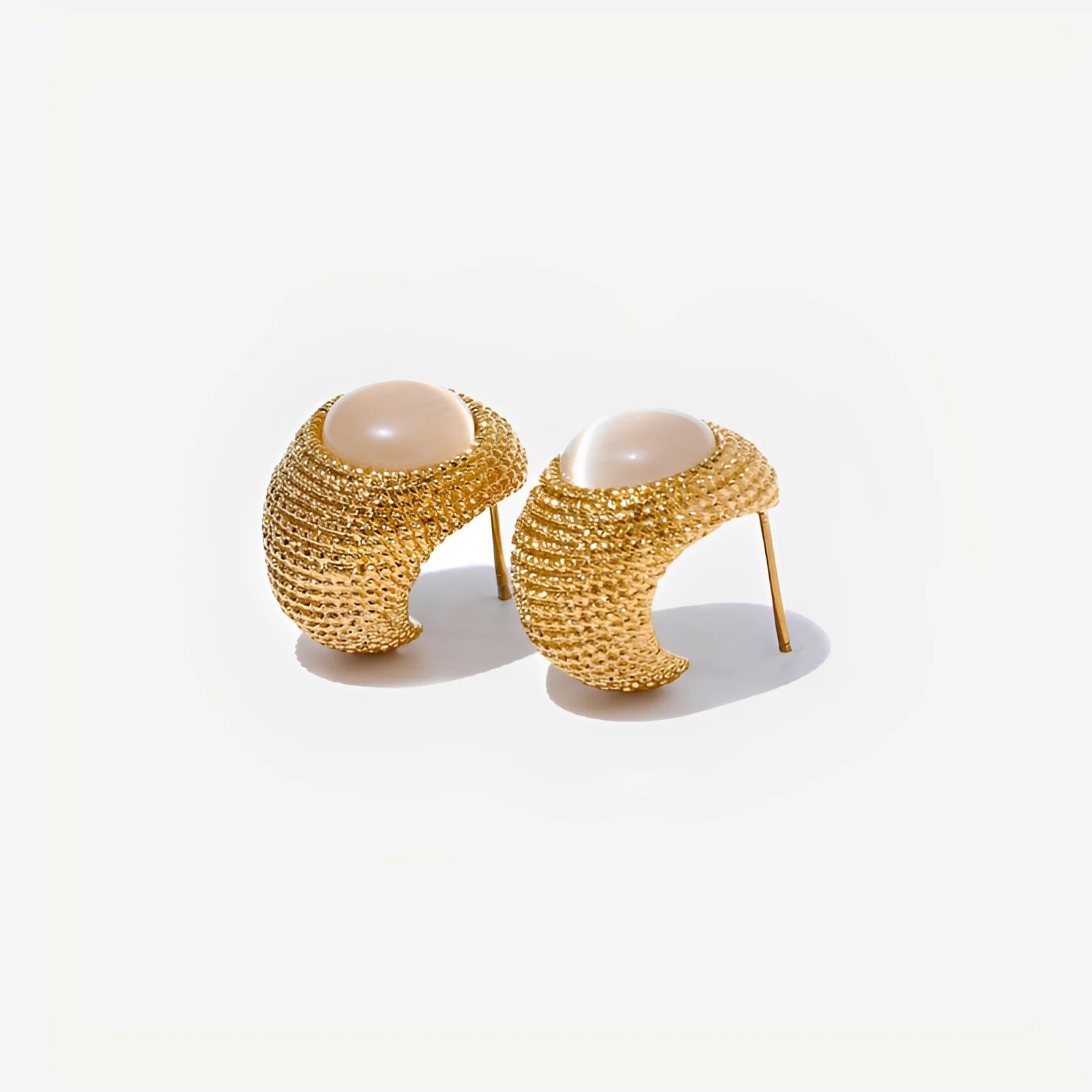 Pair of gold earrings with pearl-like centers on a white background