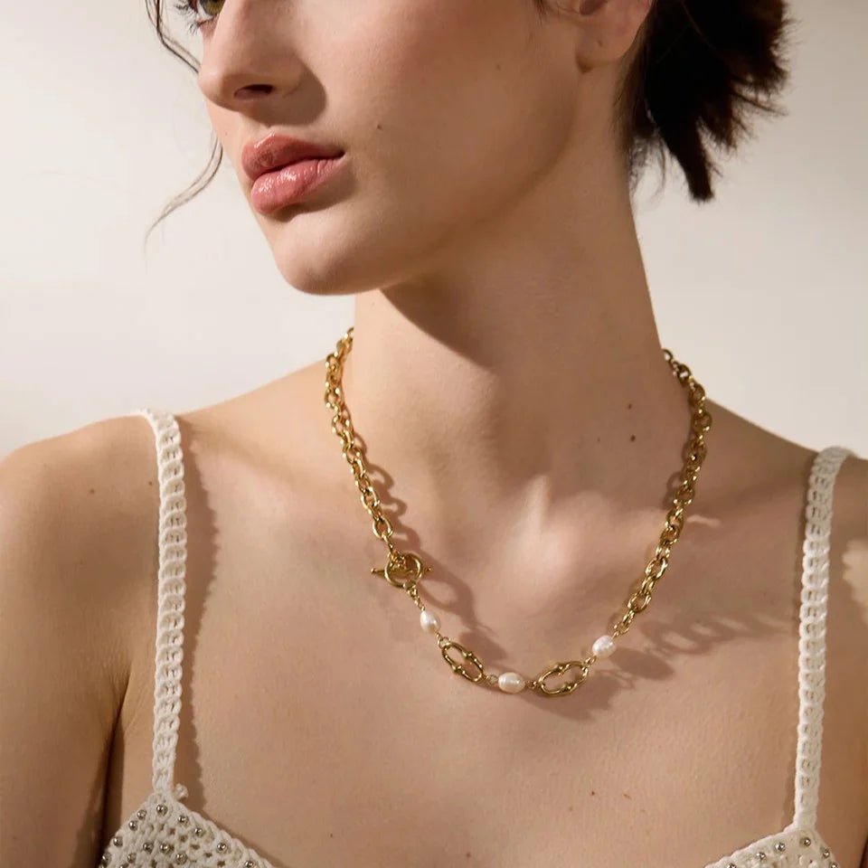 Woman wearing a gold chain necklace with pearl accents.