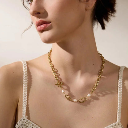 Woman wearing a gold chain necklace with pearl accents.
