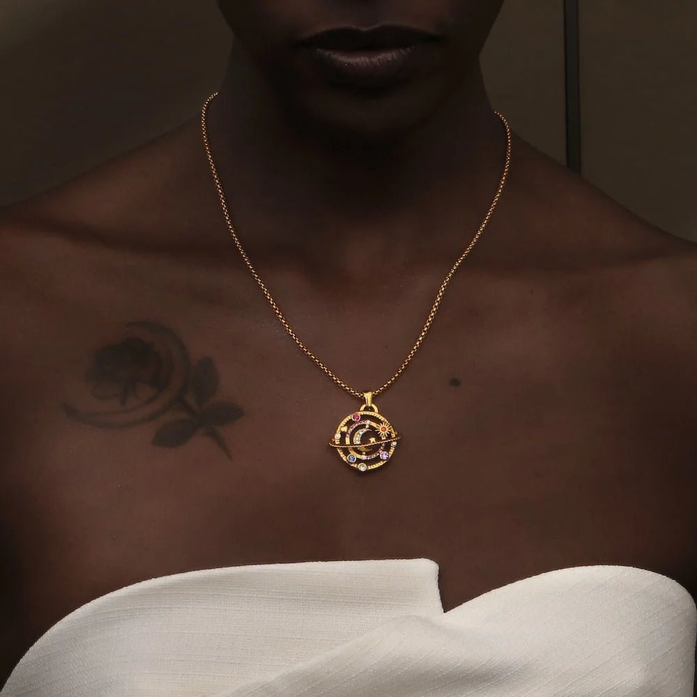 Gold necklace with a pendant on a person against a dark background