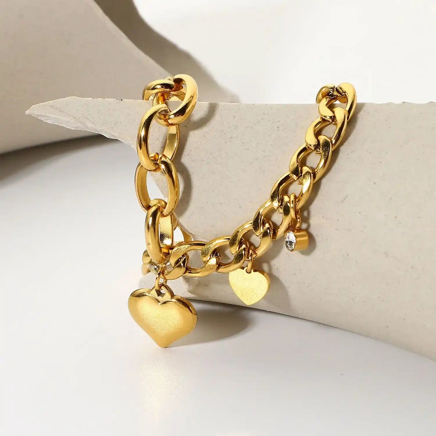 Gold chain bracelet with heart charms on a light background