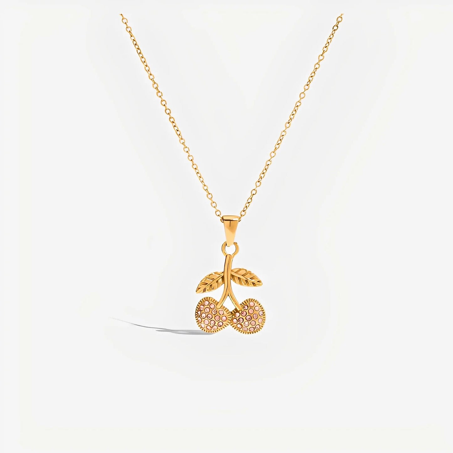 Gold necklace with a cherry pendant on a white background