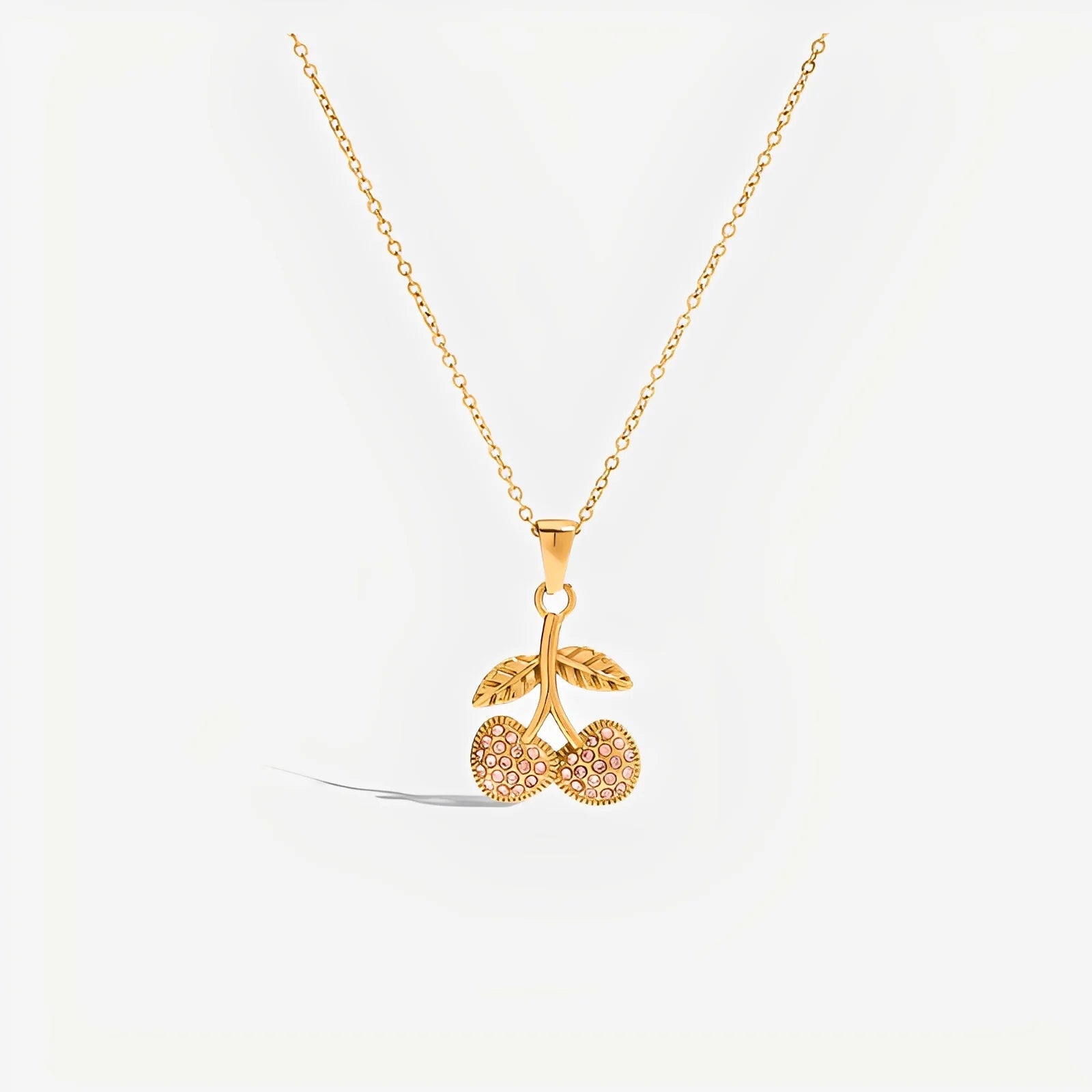 Gold necklace with a cherry pendant on a white background