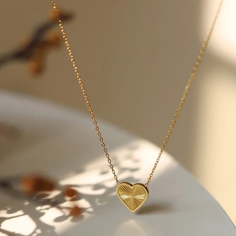 Gold heart-shaped necklace on a light surface with a blurred background