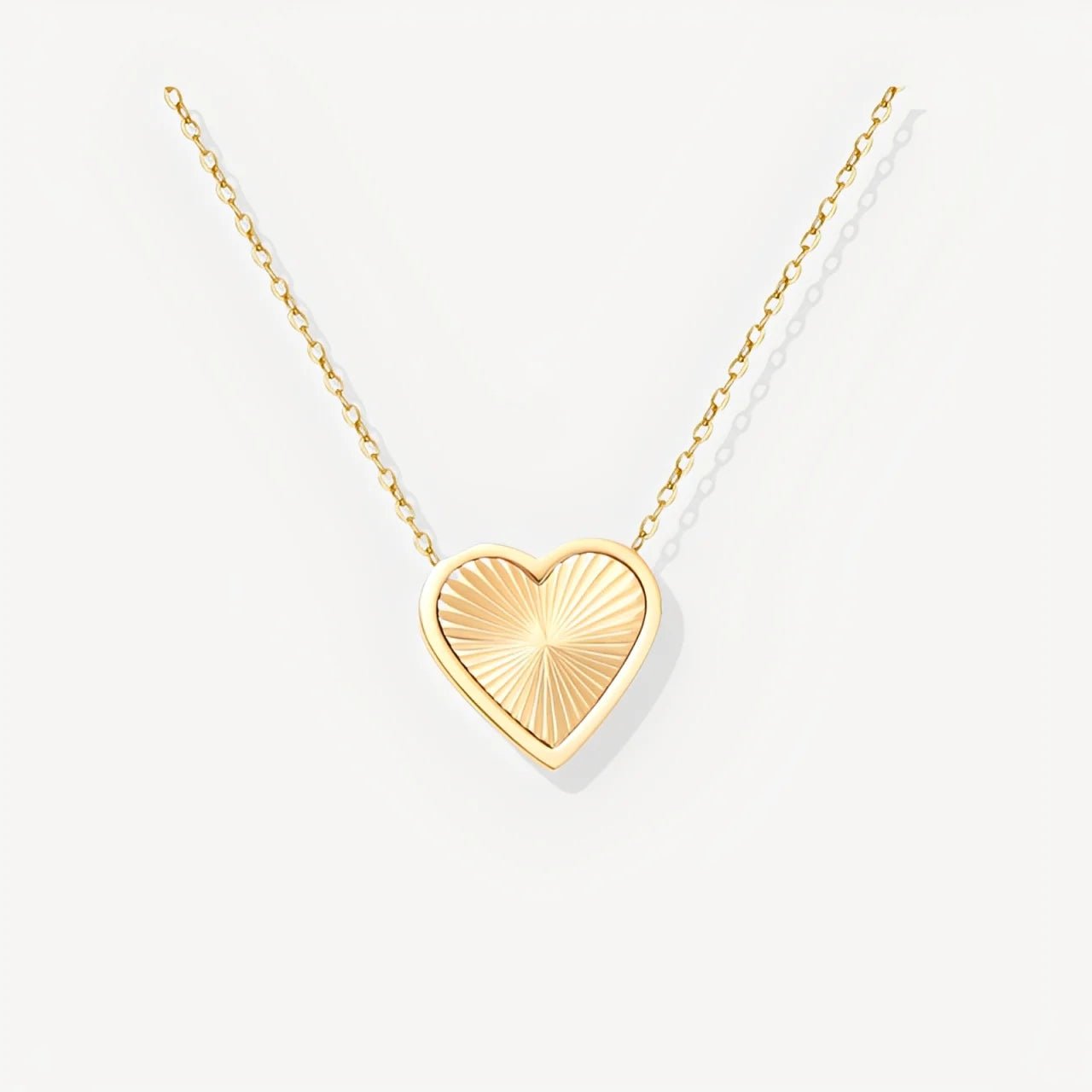 Gold heart-shaped pendant necklace on a white background