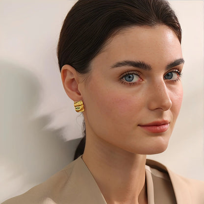 Woman wearing gold earrings with a neutral background