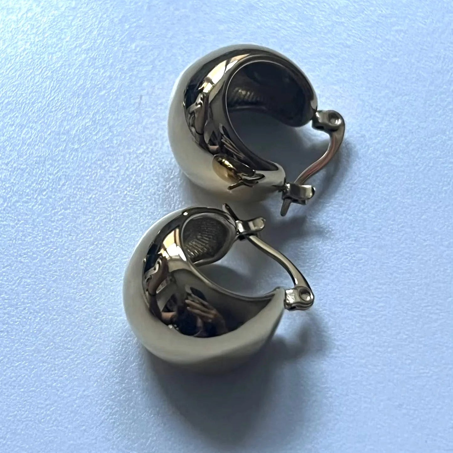 Pair of silver hoop earrings on a light blue background