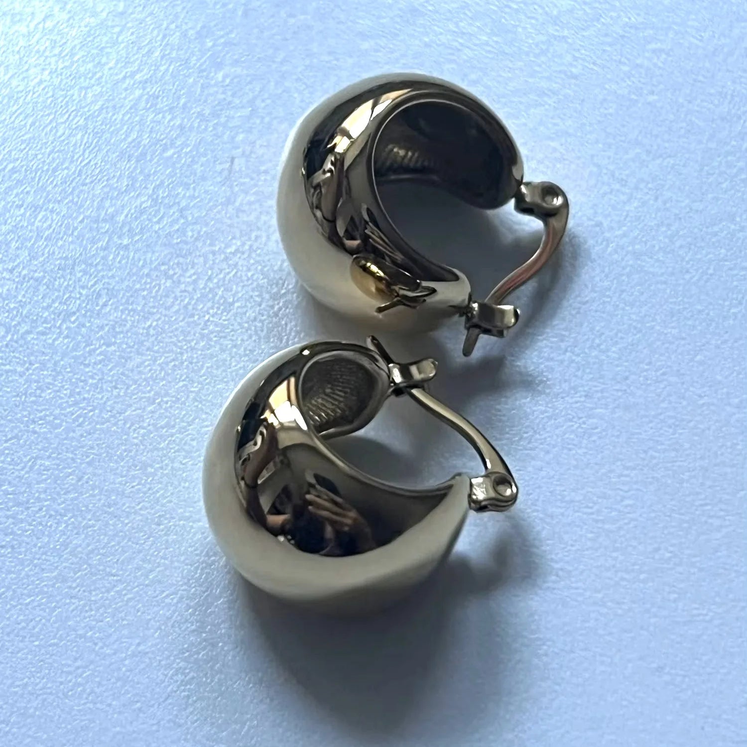 Pair of silver hoop earrings on a light blue background