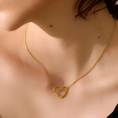 Gold necklace with a heart-shaped pendant on a person's neck