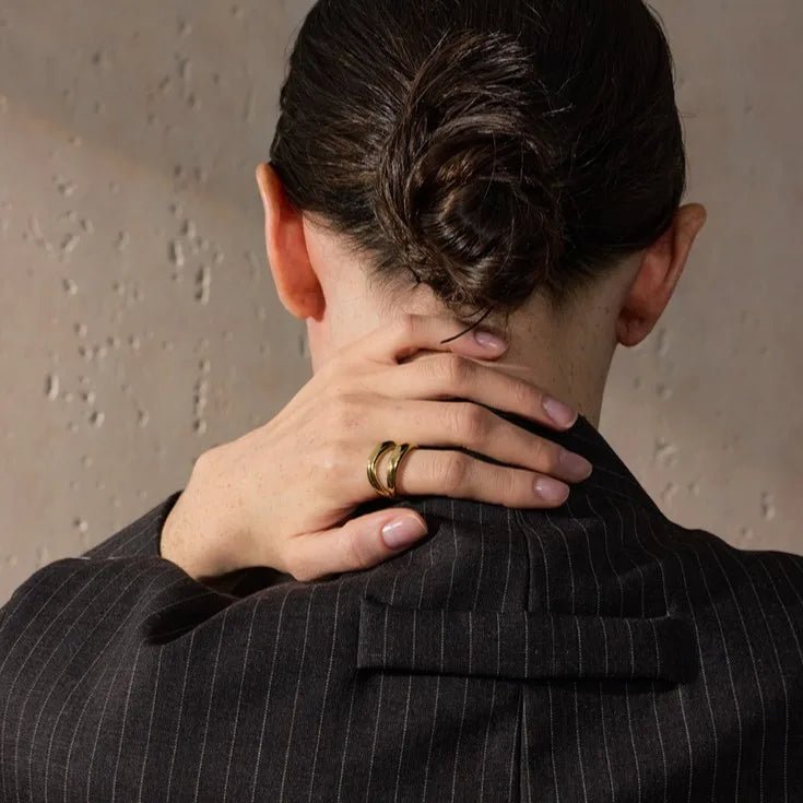 Person wearing a pinstripe suit with hands on neck against a neutral background