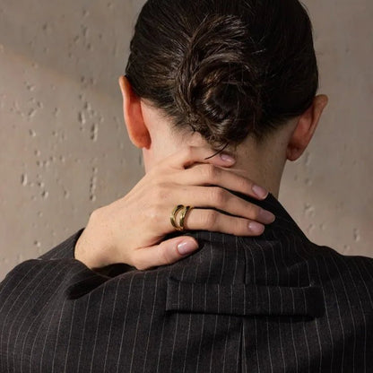 Person wearing a pinstripe suit with hands on neck against a neutral background