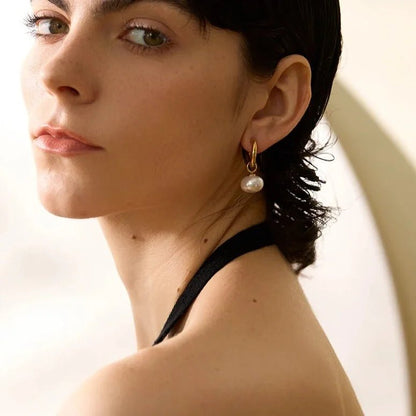 Close-up of a woman wearing pearl earrings with a neutral background