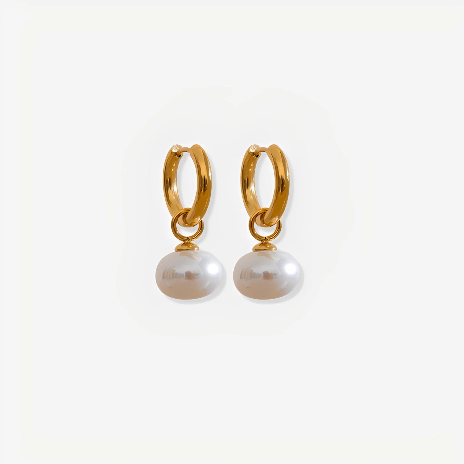 Gold hoop earrings with pearl drops on a white background