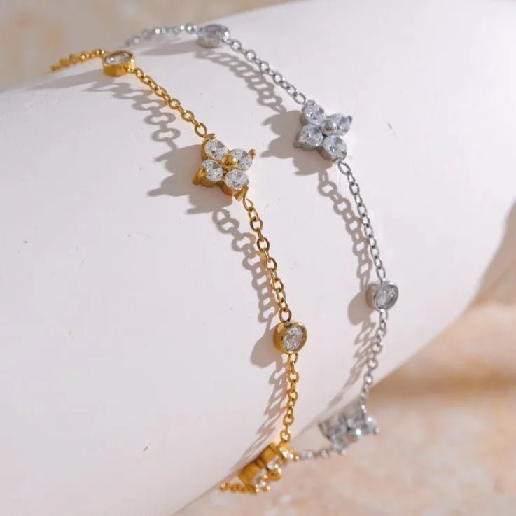 Two gold and silver bracelets with diamond-like stones on a light background