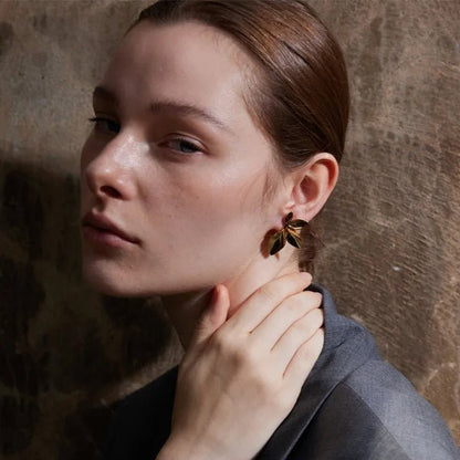Woman adjusting an earring against a textured wall